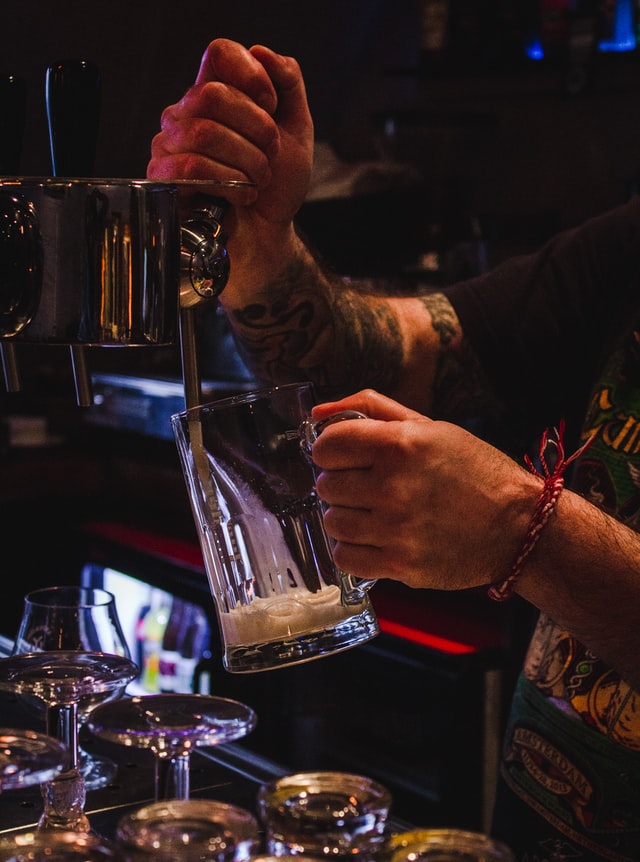 Bar staff pulling a drink through a bar tap