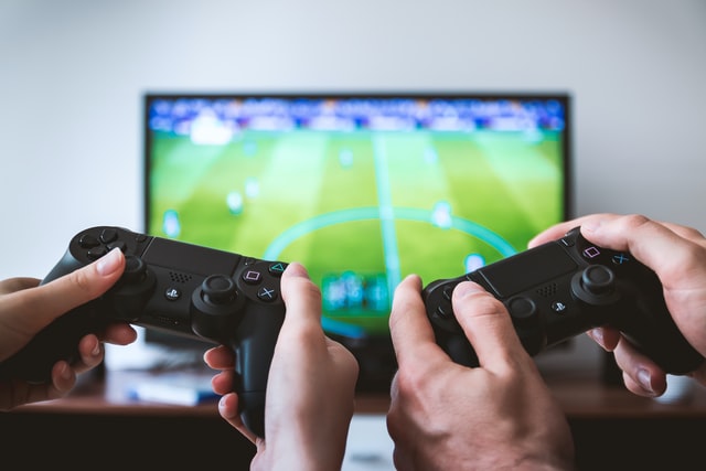 Two sets of hands holding controllers and playing a game